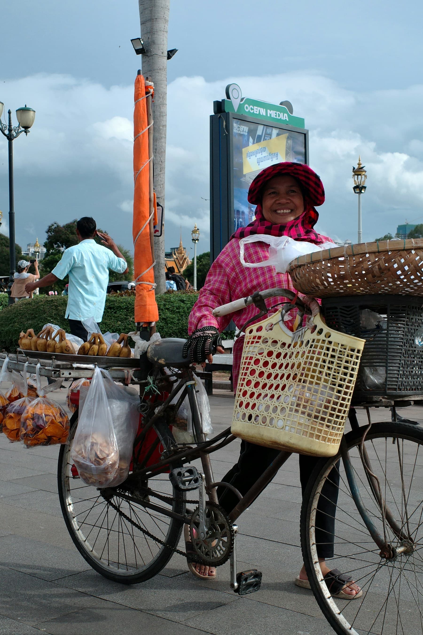 A smiling street vendor serving customers in Phnom Penh