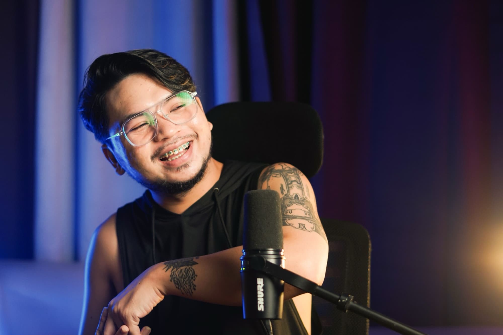 Streamer laughing beside a studio microphone during a live broadcast